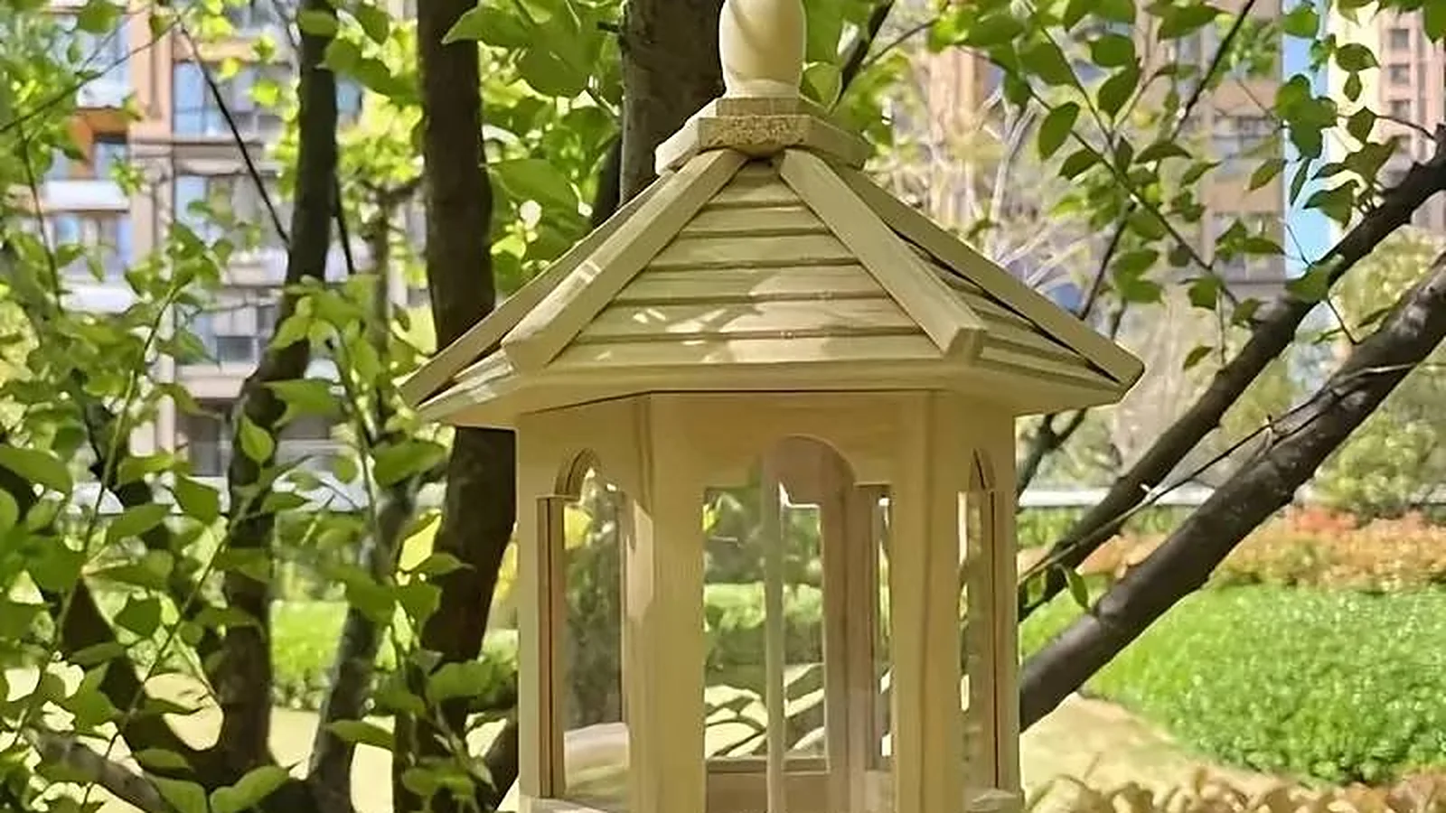Wooden gazebo bird feeder hanging in a tree